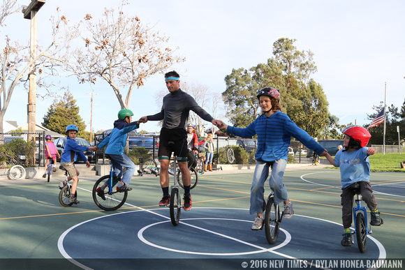 VonJon and a group of young unicyclists link hands and ride clockwise in unison at Meadow Park.