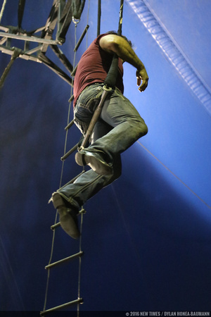 Alberto Marinelli practices trapeze in jeans, a t-shirt, and dress shoes.