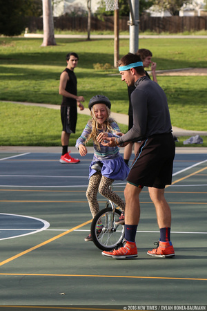 VonJon (right) helps a girl learning how to unicycle at Meadow Park.